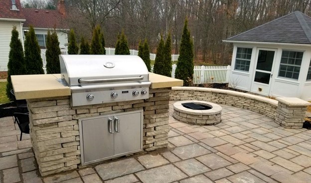 outdoor grill on stone patio with circular fire pit