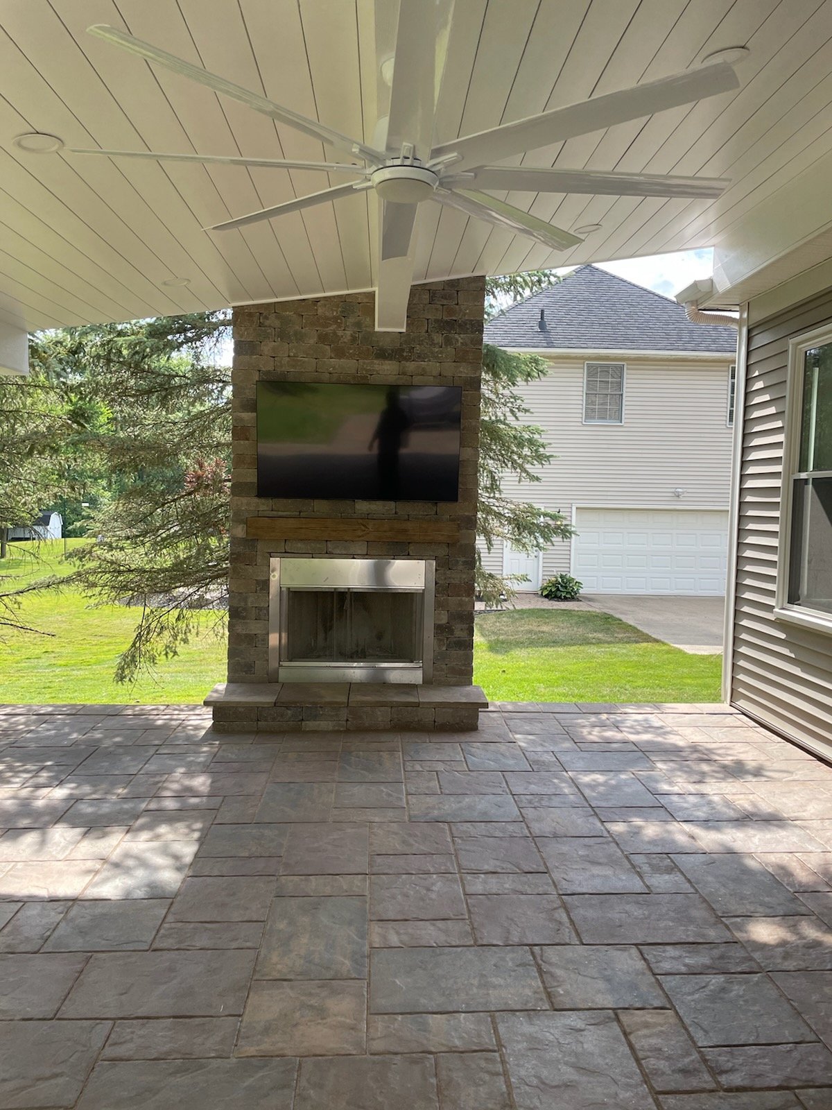 outdoor fireplace with television under covered patio